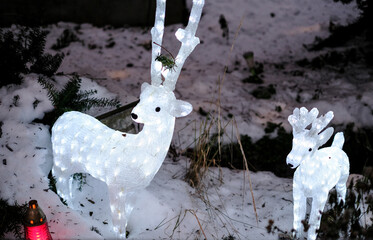Striking outdoor Christmas decoration featuring two illuminated white reindeer figures standing in fresh snow