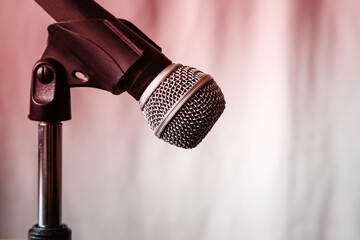 Dynamic microphone on a microphone stand against a lit curtain background close-up, dynamic...