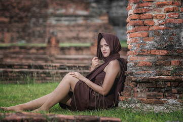 Young woman in Thai Traditional Costume sitting on  old  city in  Ayutthaya , Thailand