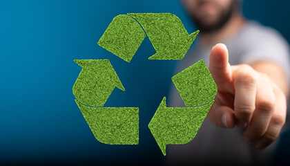 Green grass recycling symbol, sustainable eco concept.  Man points at it.