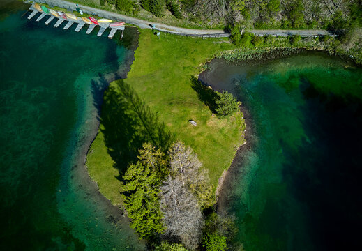 Aerial view of emerald waters embrace a verdant peninsula, contrasting with the rugged peaks in the distance, Nassereith, Tirol, Austria.