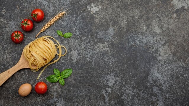 Homemade tagliatelle pasta on a wooden spoon surrounded by fresh ingredients like tomatoes, raw egg, and basil leaf on a dark textured surface. Culinary theme. Overhead shot with blank space. - Powered by Adobe