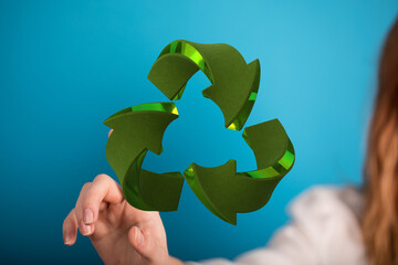 Woman interacts with a 3D recycling symbol.  Eco-friendly, sustainability, reuse.