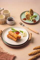 Top view of fried lumpia semarang spring rolls served with garnish and sauces. Suitable for menu design, cooking blog, or restaurant promotion