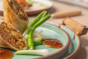 Close-up of lumpia semarang with chili, cucumber, and sweet sauce. Perfect for Asian appetizer menu or street food concept.