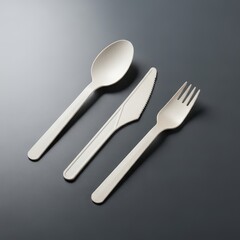 Biodegradable single-use cutlery set, spoon, knife and fork on dark background