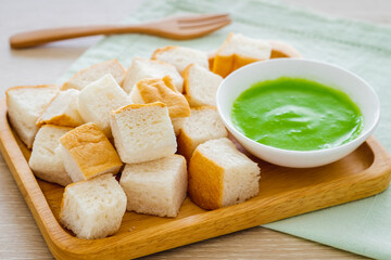 Slice steamed bread and pandan custard on wooden plate
