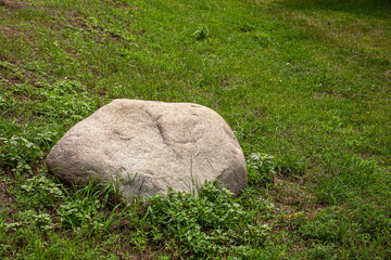 Large glacial erratic boulder resting on grassy terrain. A remnant of Ice Age glaciation, blending geology and natural landscape