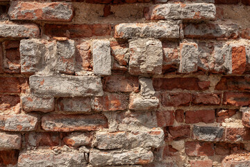 Close-up of a weathered brick wall with uneven mortar and cement patches. A textured surface...