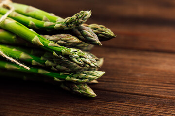 Fresh green asparagus bundled together on rustic wooden table in natural light