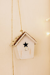 Wooden birdhouse with black star hanging on string in cozy indoor setting