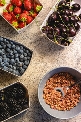 Fresh summer berries and granola on stone kitchen counter