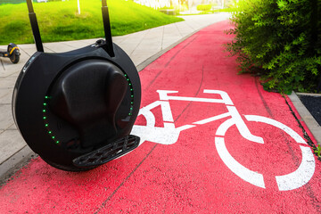 Modern unicycle parked beside bicycle lane in urban park during sunny afternoon