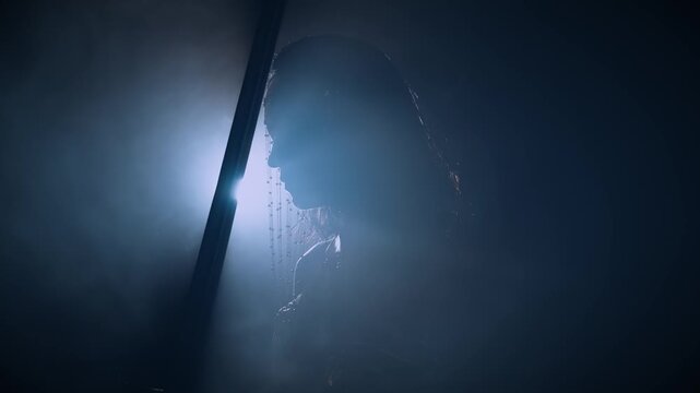 dark silhouette fantasy woman queen praying holding sword girl kneeling in dark room castle backlit ray of light hope. Black night moonlight. Elf girl warrior on knees bows head to sharp blade weapon