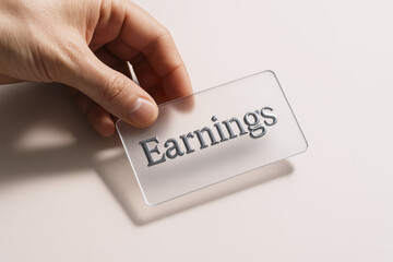 A close-up a holding a transparent acrylic card embossed with metallic lettering illustrating financial growth and income