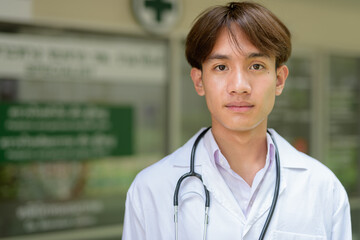 Young healthcare worker wearing lab coat in front of medical clinic