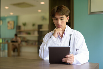 Young healthcare worker wearing lab coat sitting inside clinic library