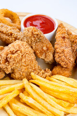Chicken fillets, wings, onion rings and fries on white background