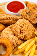 Chicken fillets, wings, onion rings and fries on white background