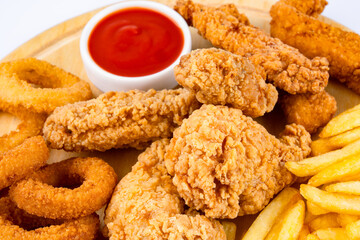 Chicken fillets, wings, onion rings and fries on white background