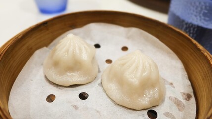 close up of two pieces of Chinese Shanghai dim sum- steamed soup pork filling dumplings in a bamboo steamer