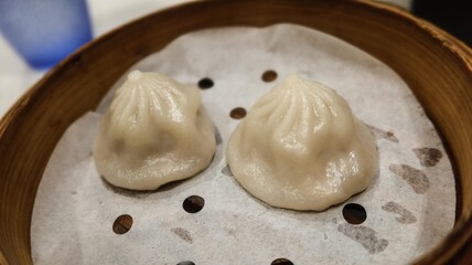 close up of two pieces of Chinese Shanghai dim sum- steamed soup pork filling dumplings in a bamboo steamer
