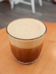 vertical photo of close up of a cold creamy black coffee with a layer of smooth foam on top with copy space