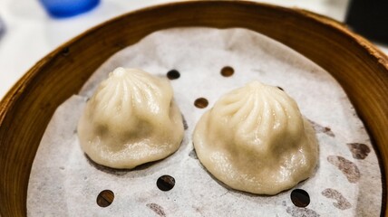 close up of two pieces of Chinese Shanghai dim sum- steamed soup pork filling dumplings in a bamboo steamer