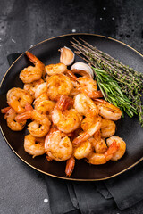Appetizing grilled shrimp prawns served on a platter, perfect for elegant dinners or casual gatherings with friends. black background. top view