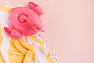 Beach essentials including an inflatable flamingo and towel on a light background.