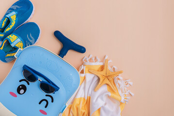 Children's beach essentials including a suitcase, shoes, sunglasses, towel, and starfish.