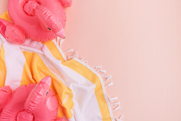 Beach essentials including an inflatable flamingos and towel on a light background.