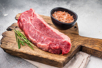 Uncooked striploin steak or strip New York on a wooden cutting board, inviting you to create mouthwatering recipes for any occasion. white background. top view