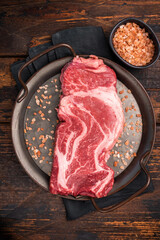 Prime Raw Chuck eye roll steak, fresh beef meat in steel tray. wooden background. top view
