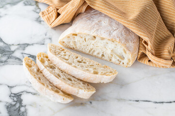Italian baked and sliced ciabatta bread on a marble table. marble background. top view
