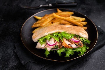 Turkish Shawarma, Doner kebab with grilled chicken meat in pita bread on a plate with french fry. black background. top view