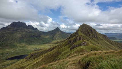 Obraz premium Scenic view of rugged Scottish mountains featuring jagged peaks and rolling green hills under cloudy sky landscape during summer.