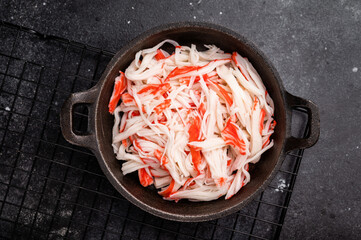 japanese Crab meat, crabmeat imitation in a skillet. black background. top view