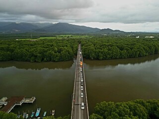 Morning traffic on bridge with river and mangrove area.