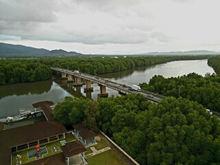Morning traffic on bridge with river and mangrove area.