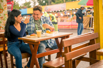 A couple of friends enjoy food during their visit to their city's fair.