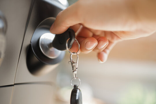 Hand inserting a car key into the ignition switch in a vehicle dashboard 
