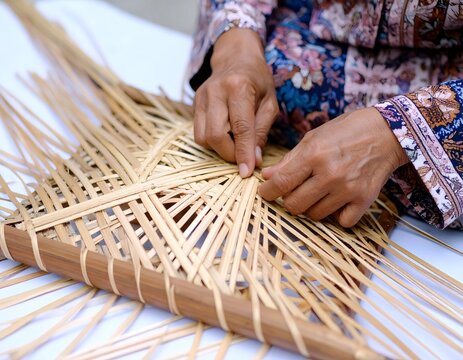 Close up of hands weaving traditional bamboo craft creating intricate pattern