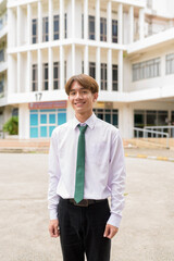 Happy non binary university student smiling in college campus