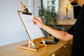 Artist painting on easel in home studio setting