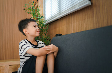 Young boy sits on a couch looking out the window 
