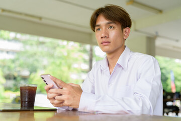 Obraz premium Non binary university student sitting in college campus using phone