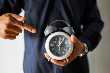 Unrecognizable businessman with an alarm clock in a hand 

