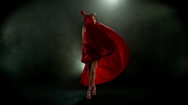 Brunette Woman in Ruby Red Dress Posing Against a Black Background . Filmed on High Speed Cinematic Camera in Super Slow Motion