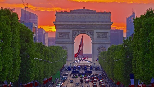 Arc de Triomphe against the backdrop of a beautiful sunset. French flag in the wind in the triumphal arch. Paris, France